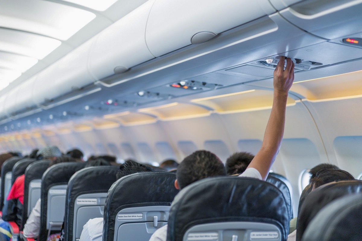 man adjusting plane air vent