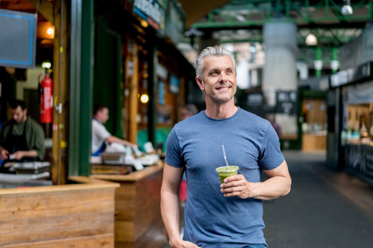 white man with gray hair drinking a smoothie outside