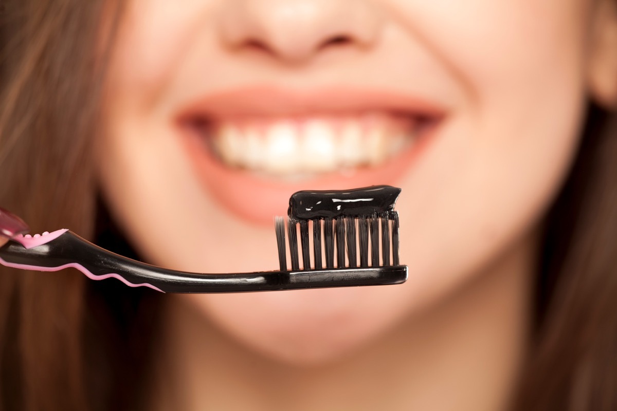 Woman brushing her teeth with activated charcoal