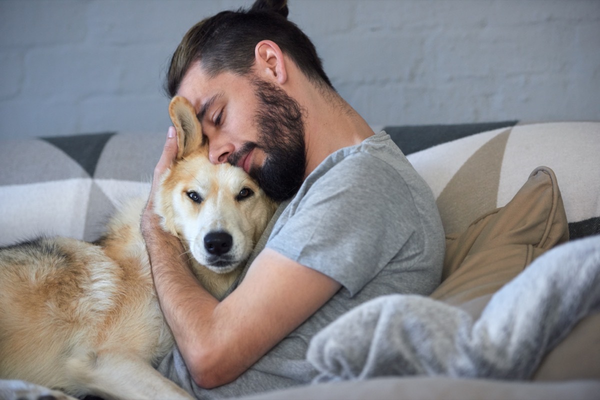 man snuggling and hugging his dog, close friendship loving bond between owner and pet husky