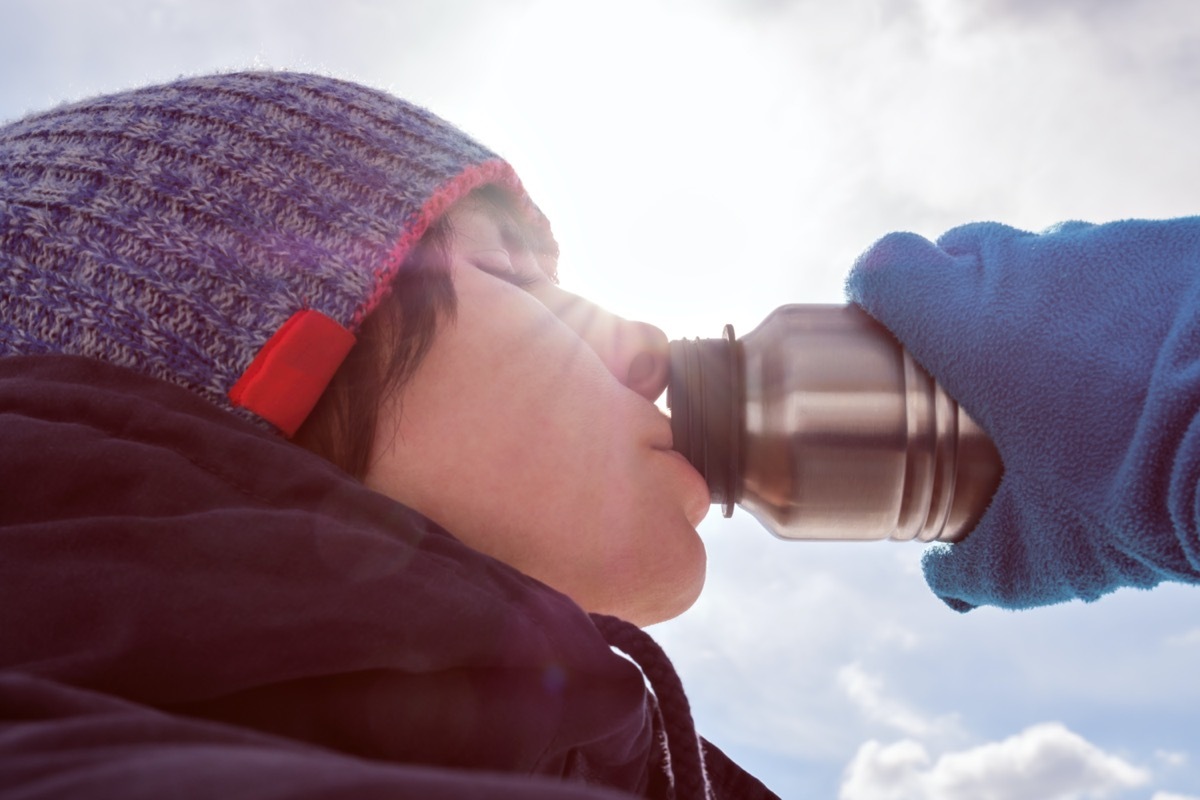 winter clothes eagerly drinks water from a bottle