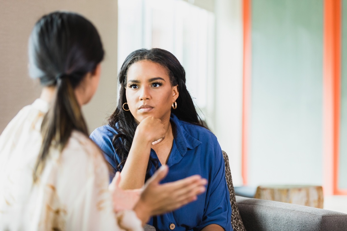 During a counseling session, the unrecognizable mid adult female patient gestures while speaking. The mid adult female therapist listens attentively.