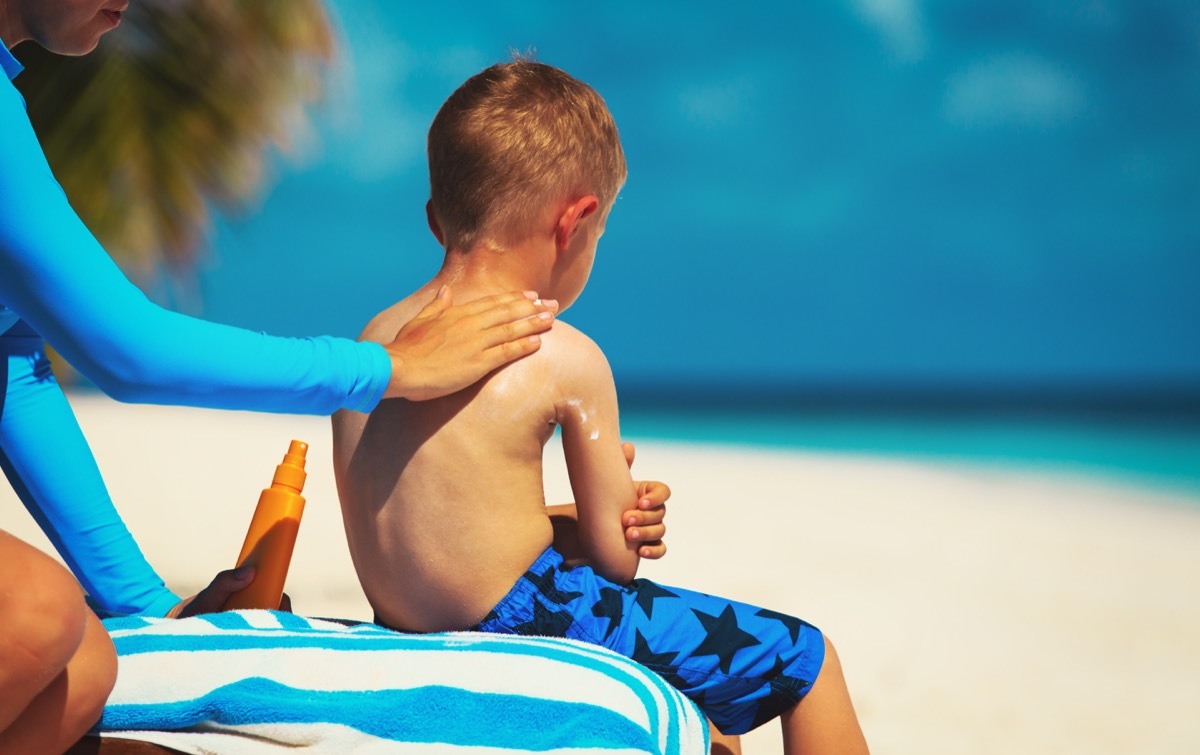 Mom applies sunscreen to child's back on beach, skin cancer facts