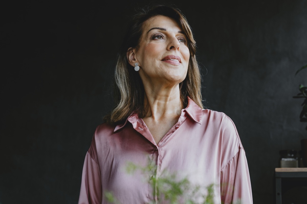 Elegant smiling mature woman standing in front of a dark background