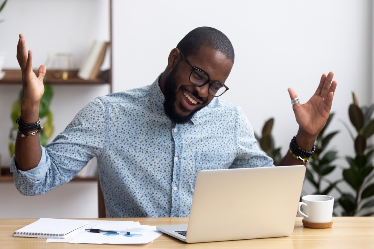 black man sitting at desk looking at computer screen talking on video call