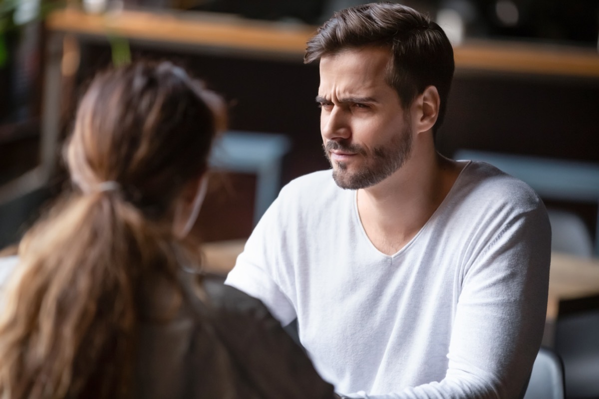 Young couple sitting at table in cafe, talking.