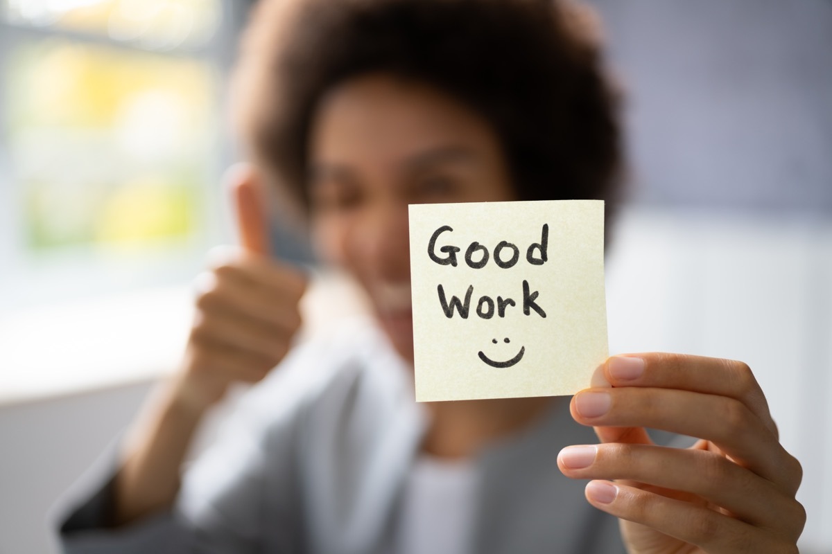 woman holding up a sticky note saying 