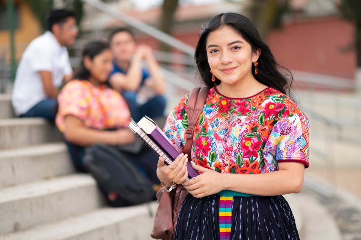 college student standing on steps with books in her hand