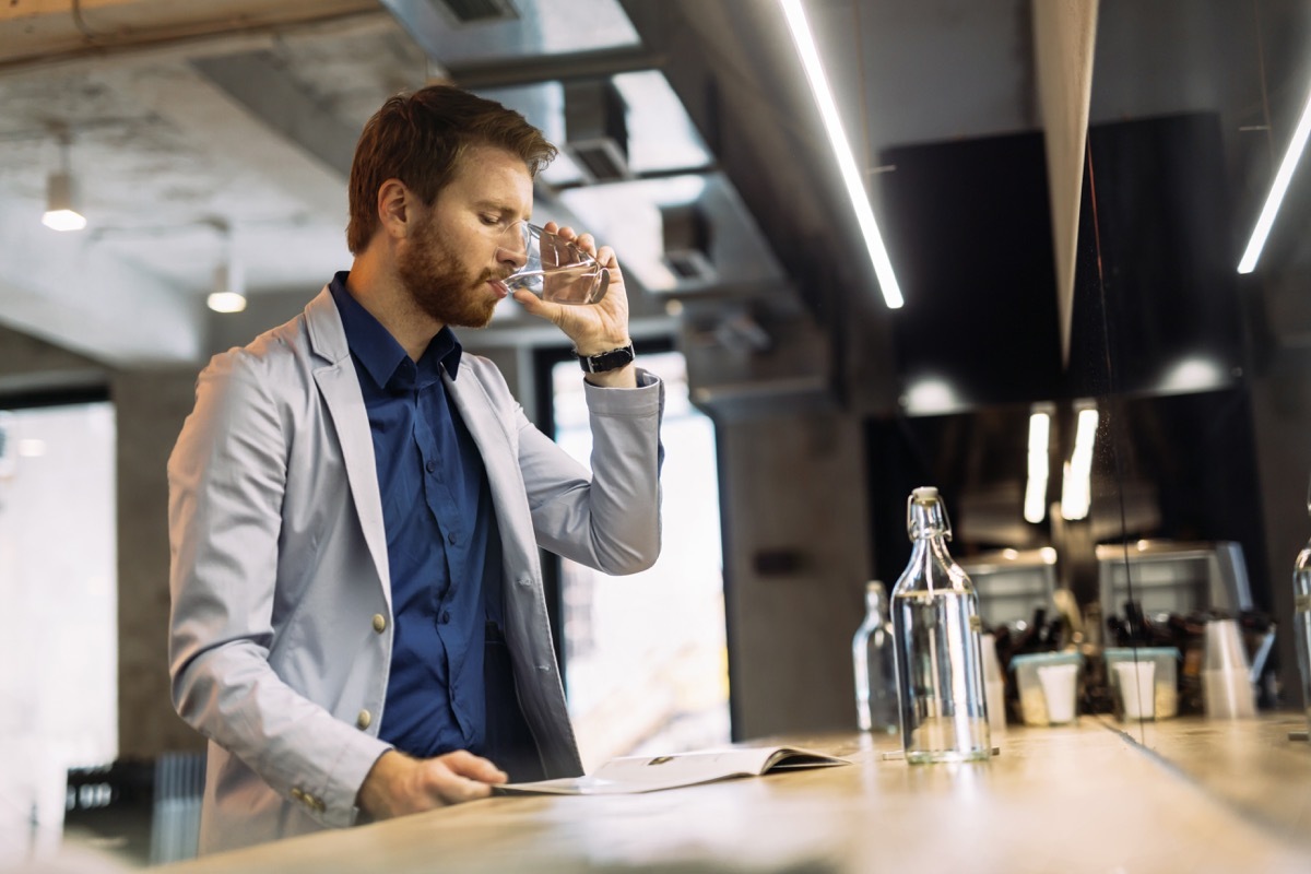 Man=n drinking a glass of water while reading