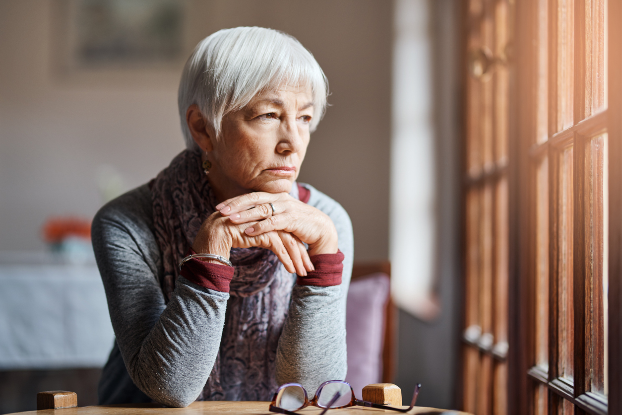 A senior woman looking out her window.