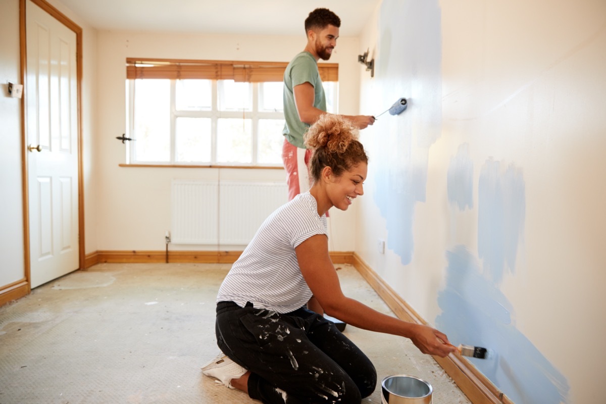 young couple painting wall with rollers