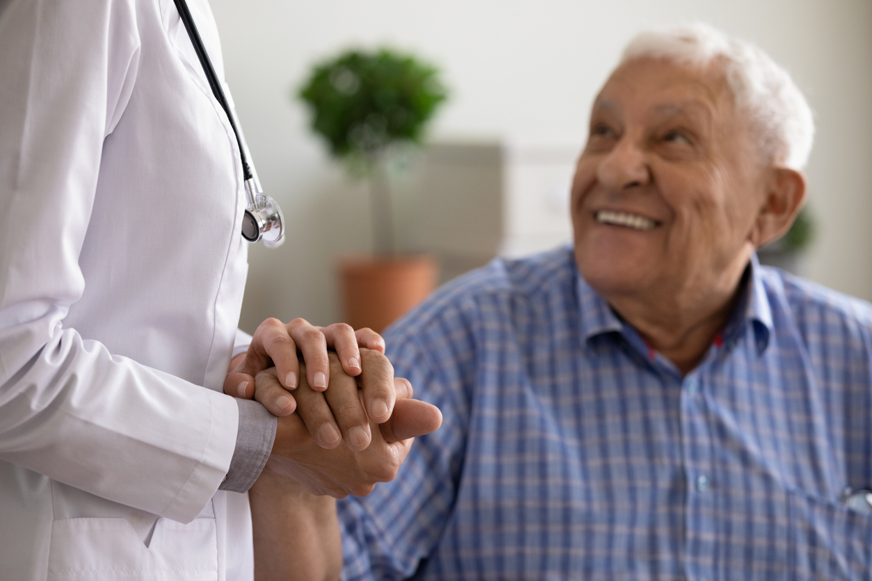 A senior male patient holding a doctor's hand in a checkup