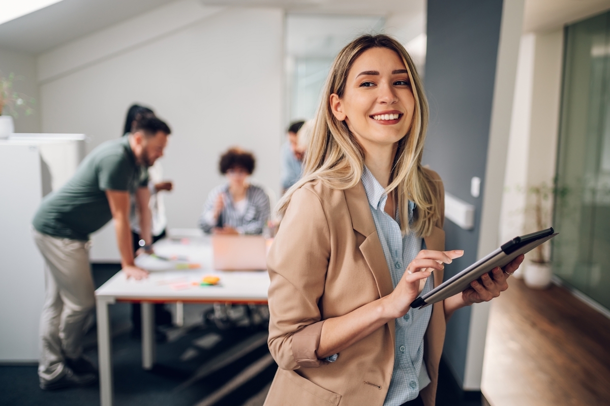 Woman in boardroom with colleagues using tablet