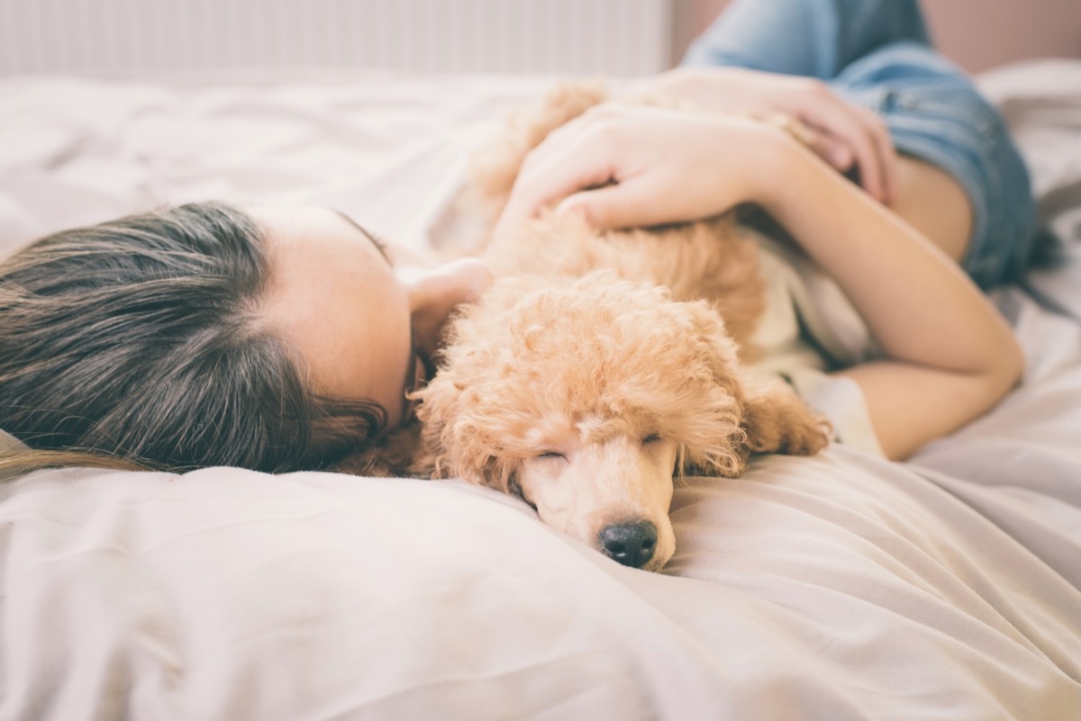 woman sleeping with dog on bed