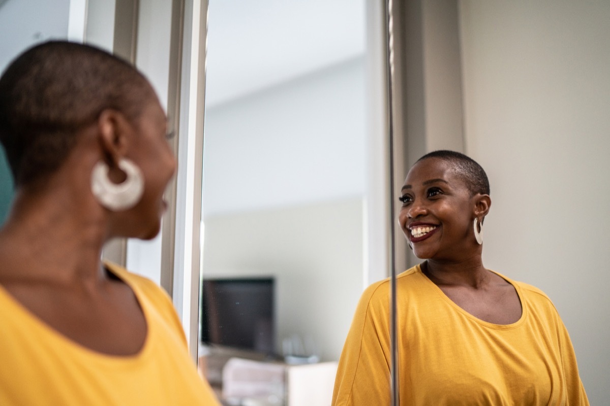 Mid adult woman looking in the mirror at home