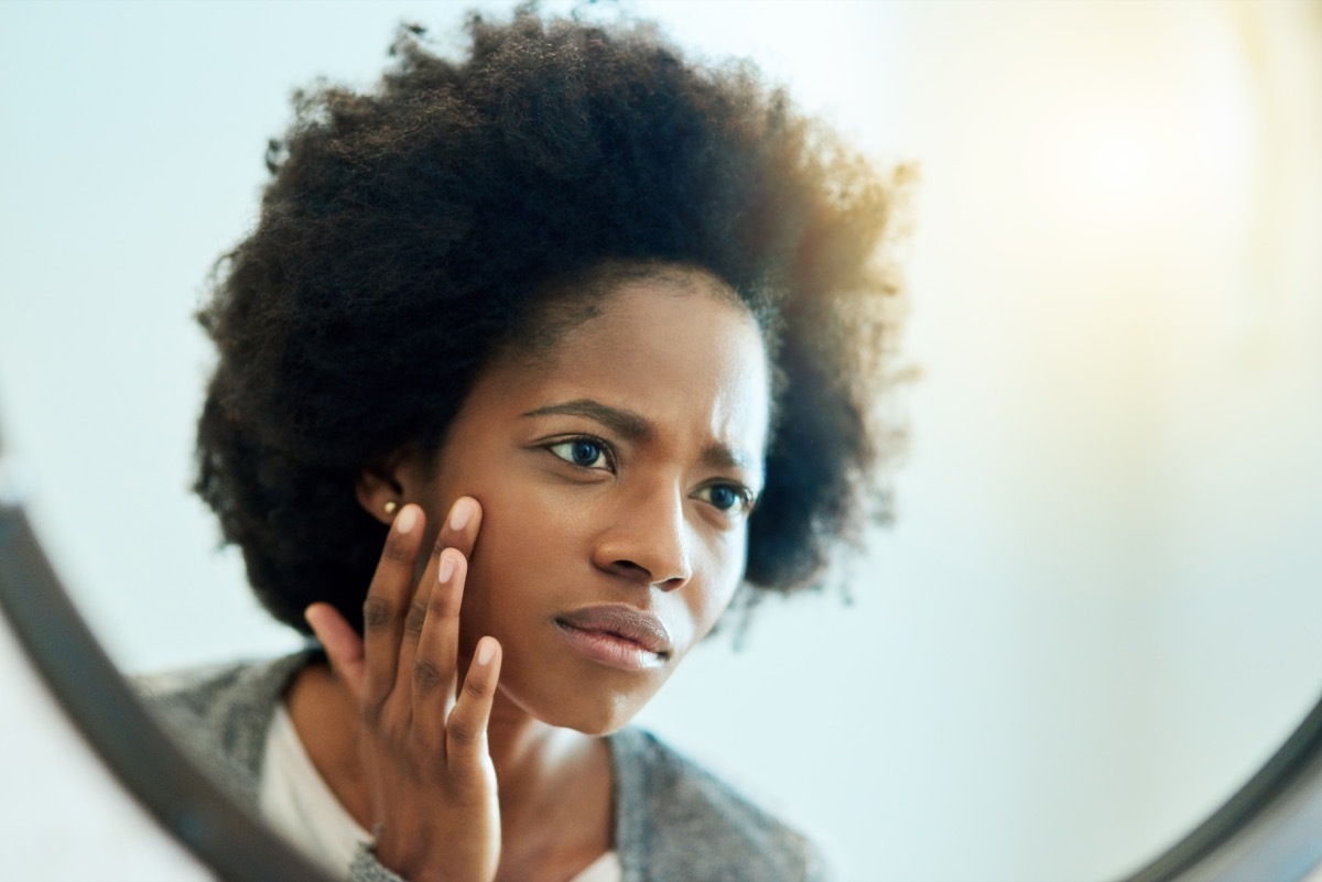 Shot of an attractive young woman inspecting her face in the bathroom mirror