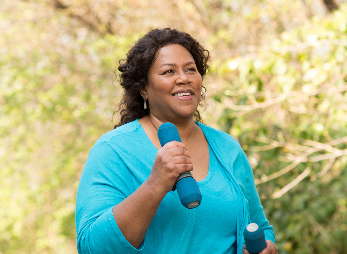 older woman walking with hand weights outside