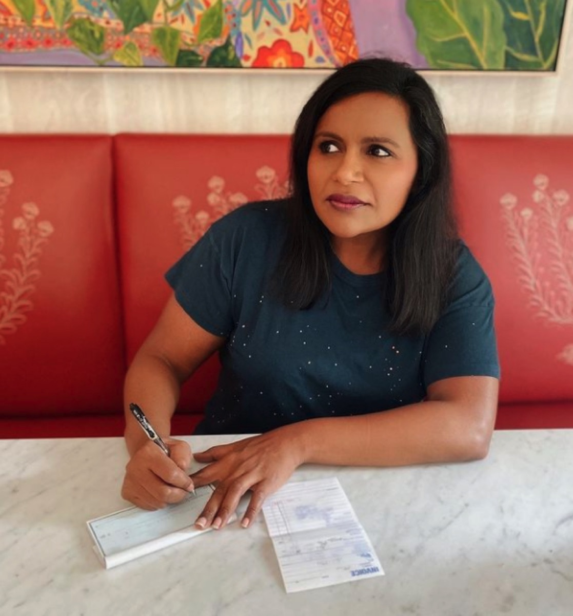 Mindy Kaling writing a check