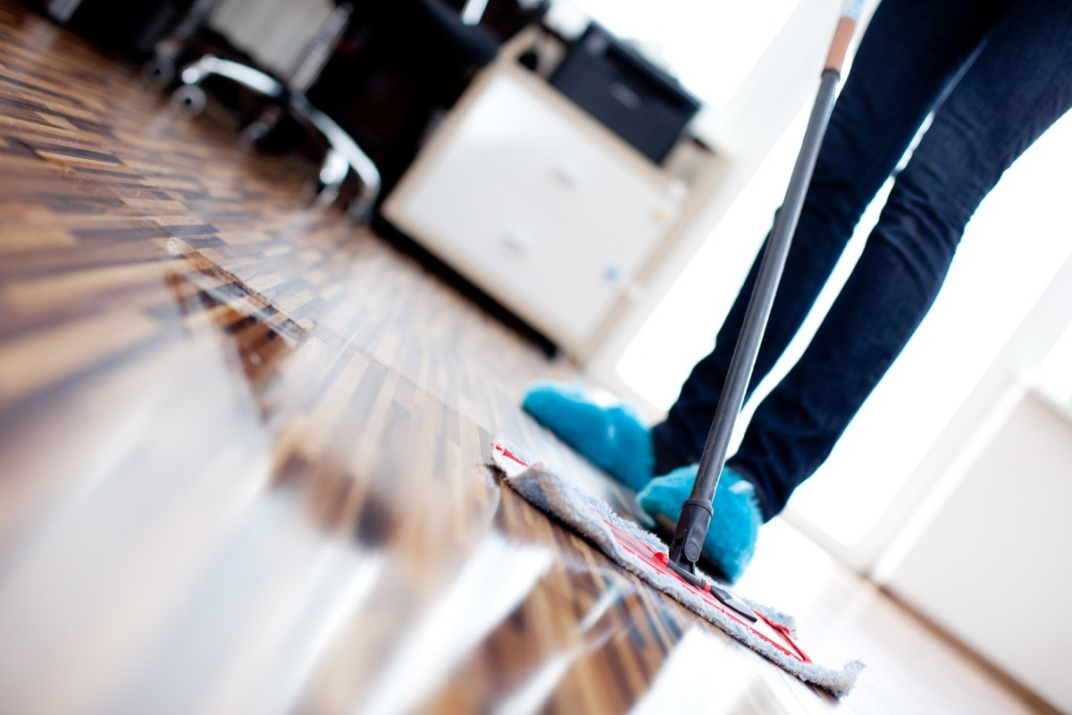 person using mop to clean hardwood floor