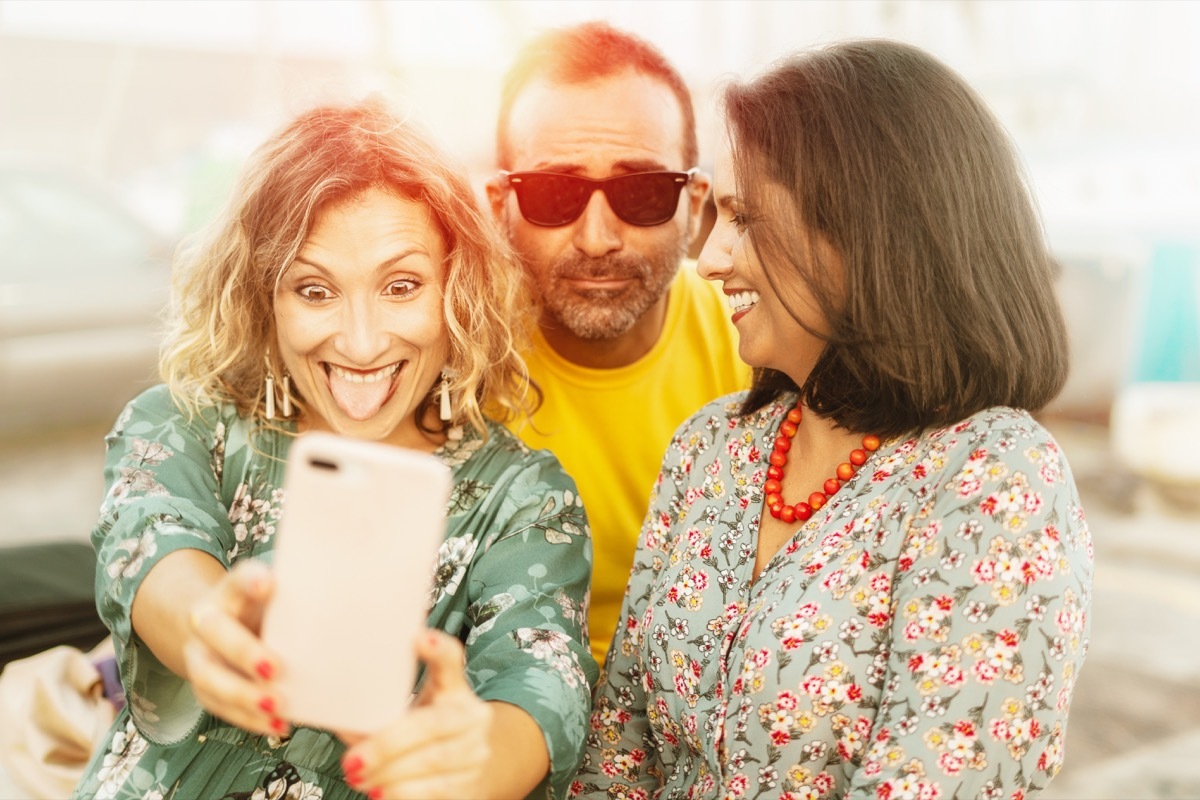 Middle aged friends being silly having fun taking selfies with phone