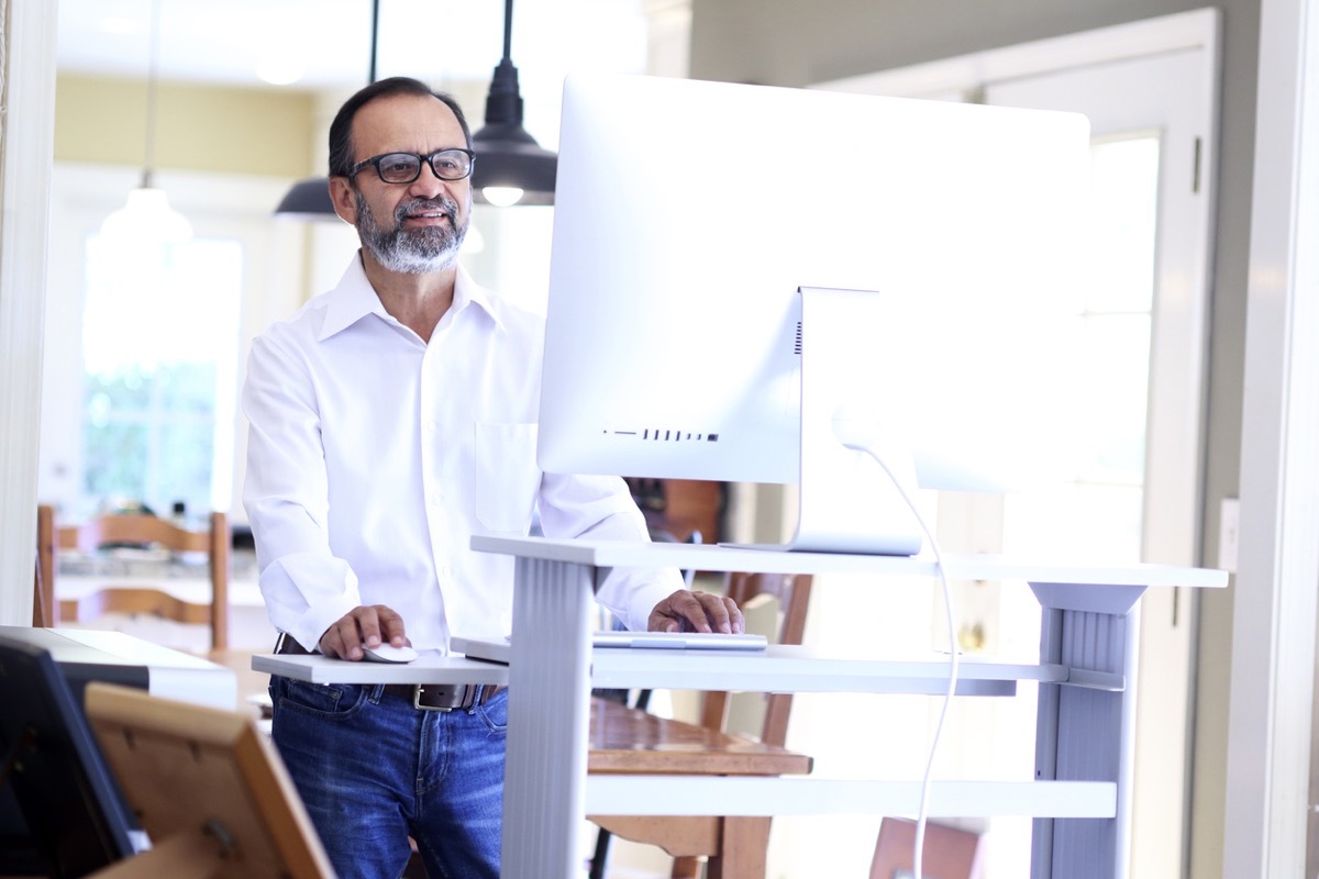 middle aged latino man working at a standing desk in his home