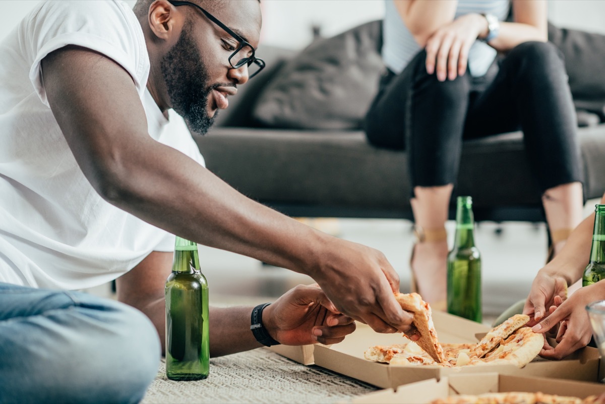 man eating pizza and drinking beer on floor, healthy sex after 40