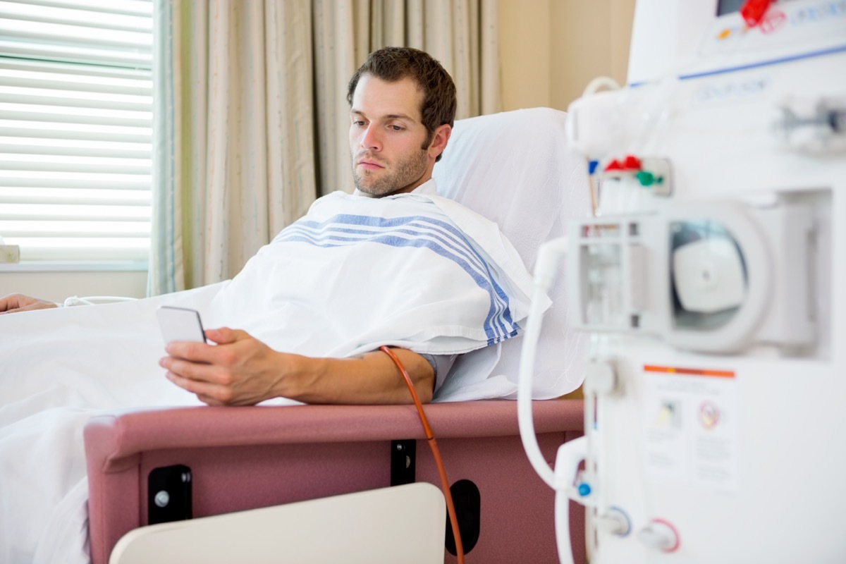 Man using his phone while getting dialysis