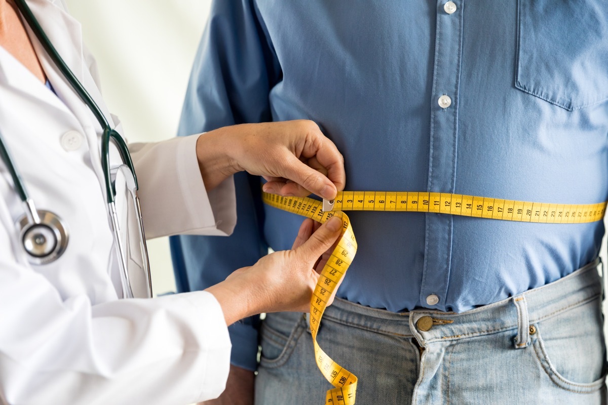 doctor measuring overweight man's waist