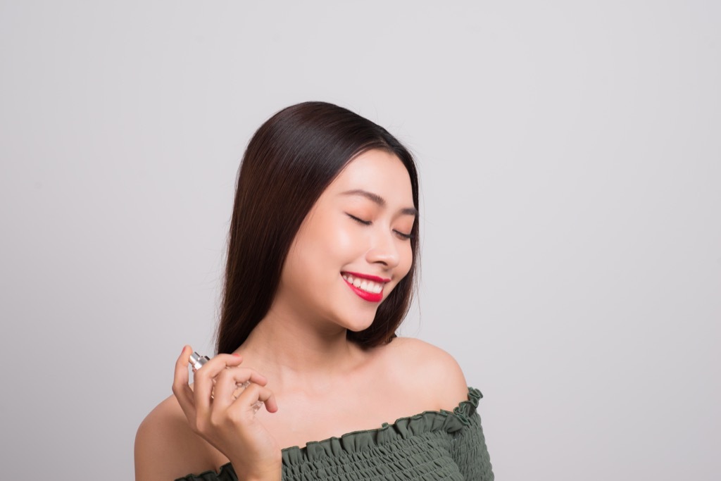 woman spraying perfume on her neck