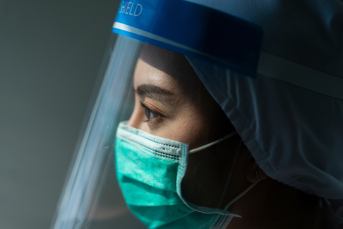 doctor looks stressed in mask and face shield amid coronavirus