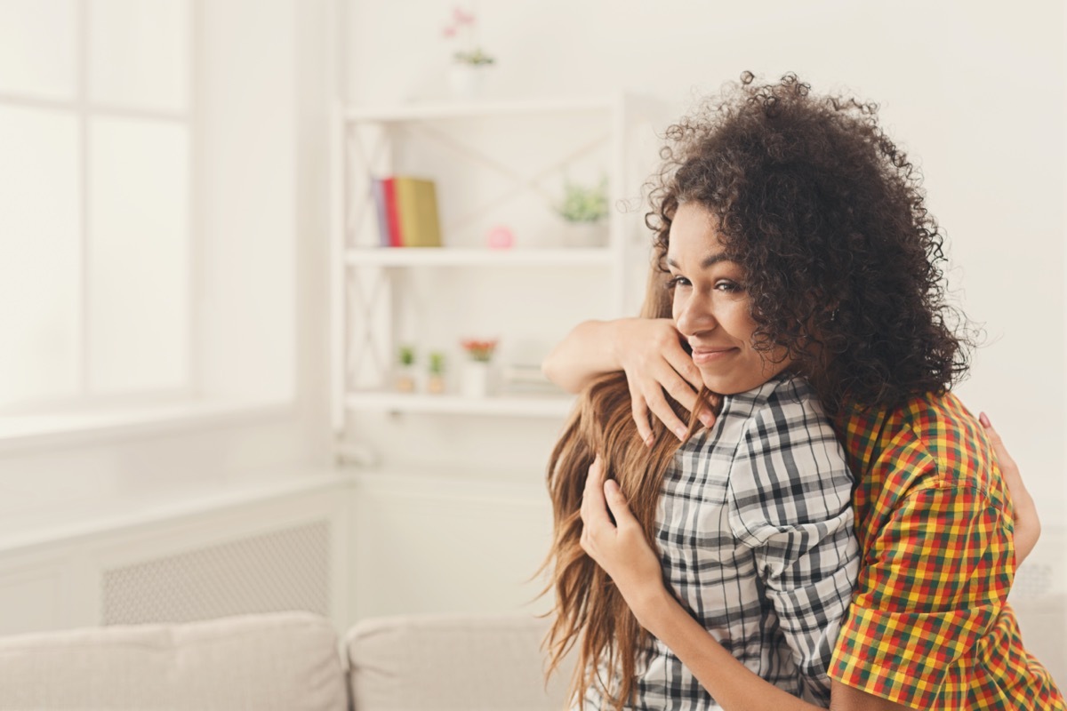 Two female friends embracing each other at home