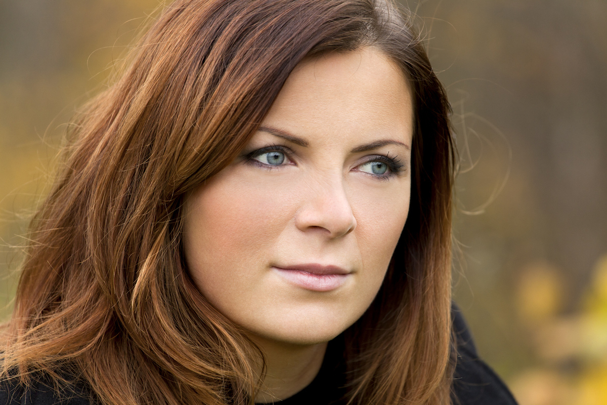 Portrait of a woman outside with brown hair that has rust-colored highlights