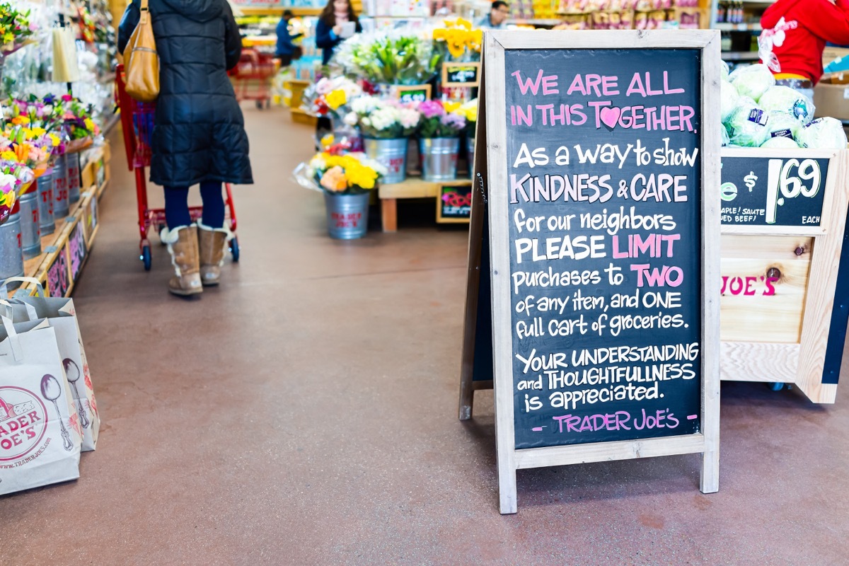 Reston, USA - March 18, 2020: Trader Joe's store inside indoors saying making request for customers to limit purchase to two items and full grocery cart with people and shopping cart