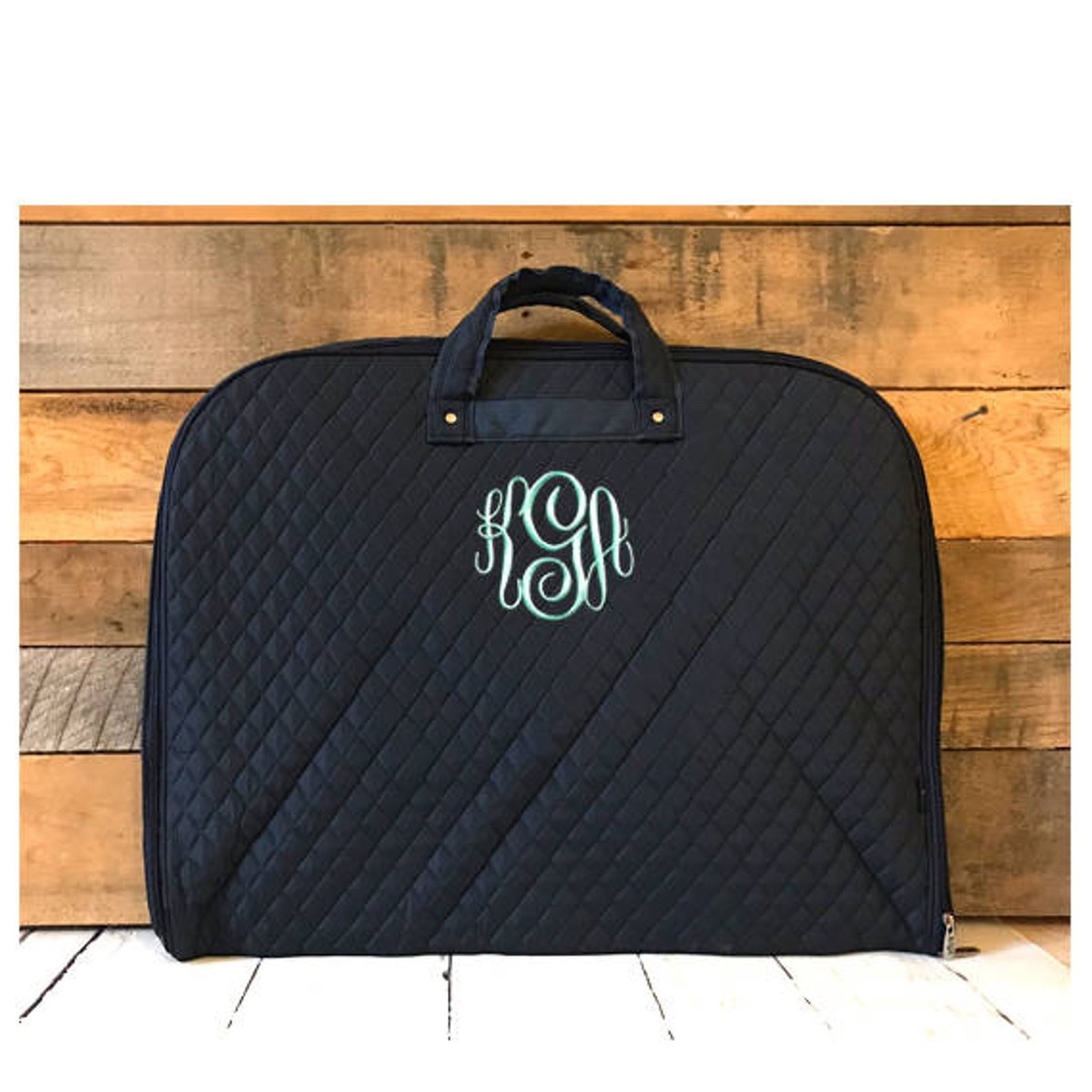 Black quilted garment bag, wood background