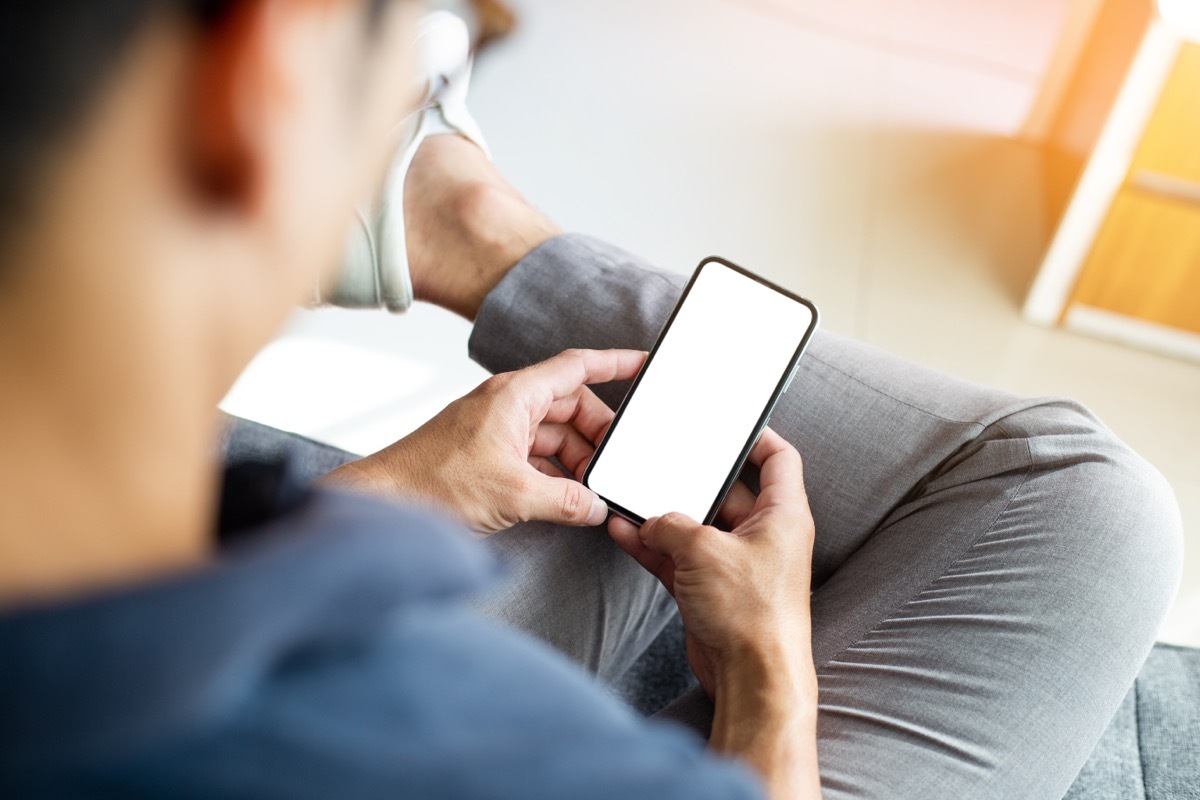 Man texting on his phone in a blue shirt.