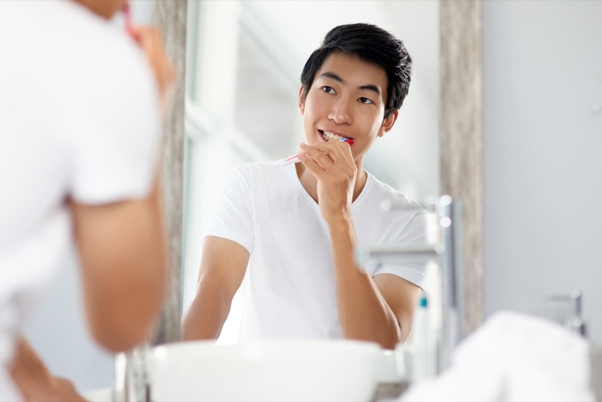 Shot of a handsome young man brushing his teeth in the bathroom at home