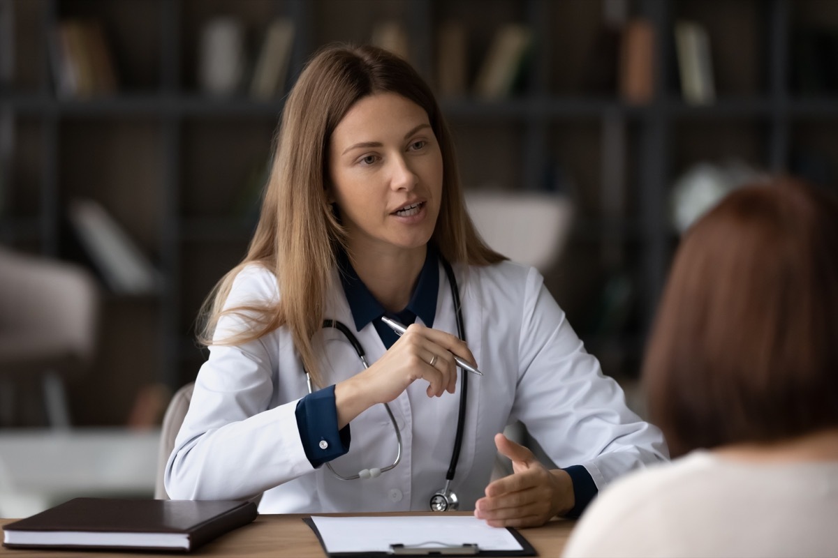 Female doctor therapist in white uniform with stethoscope consulting woman patient at meeting, sitting at desk in hospital, giving recommendations, explaining medical checkup results at appointment