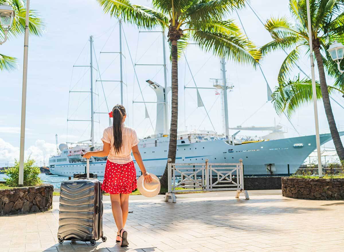 a woman walks with her suitcase toward a cruise ship