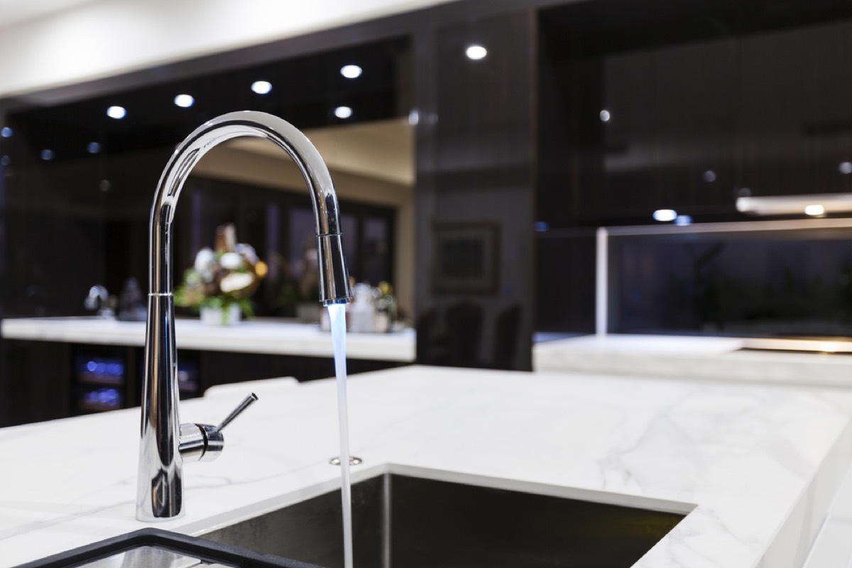 modern silver faucet with running water into sink