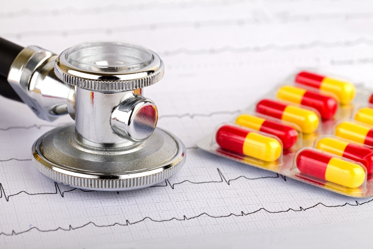 Electrocardiogram graph report with stethoscope and pills on it