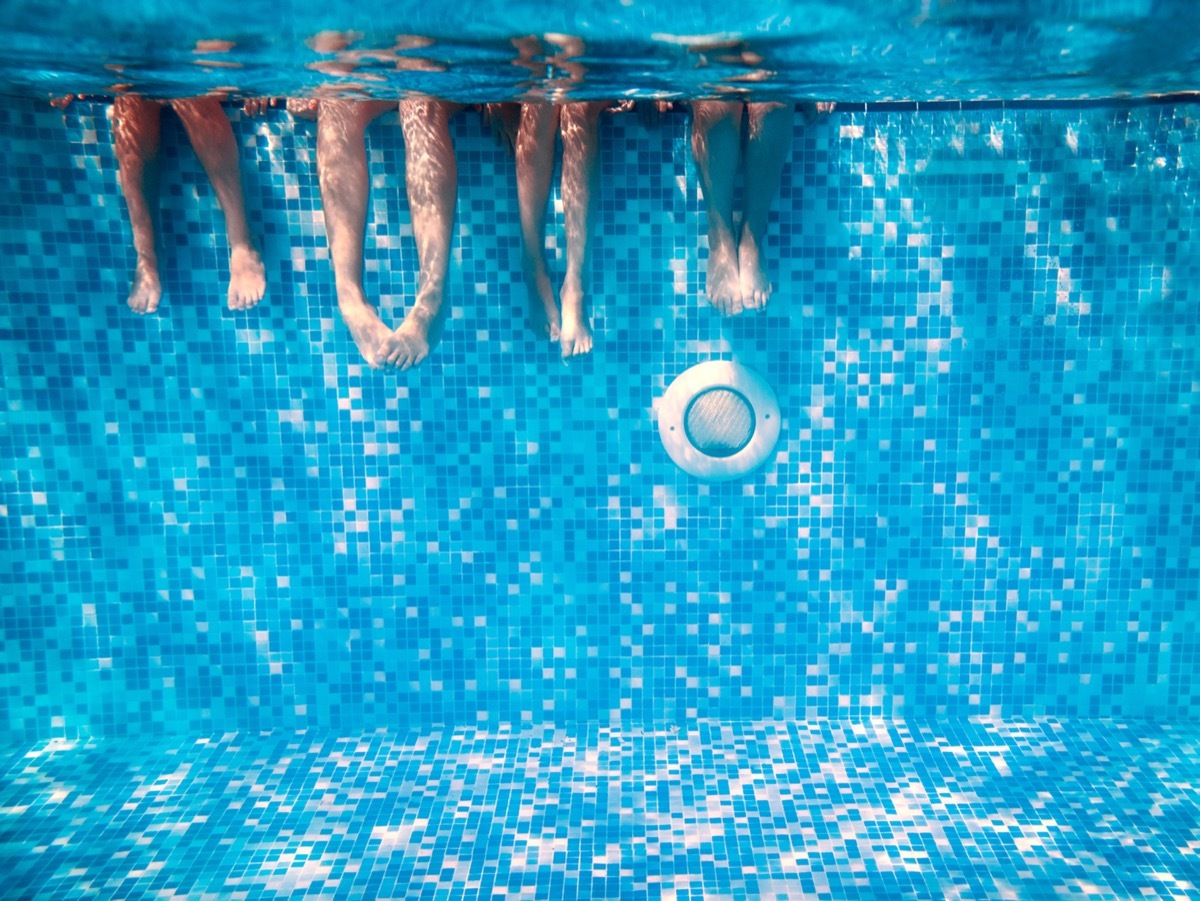 Children's and adults legs underwater in the swimming pool