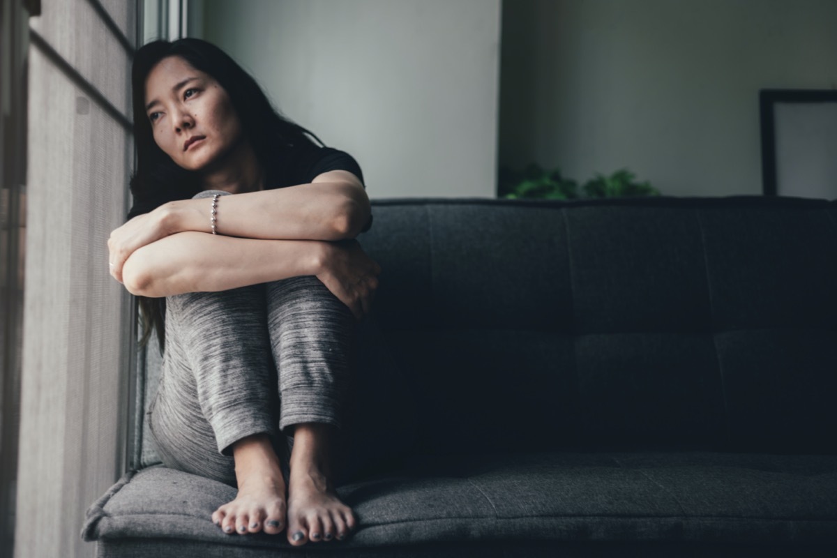 Depressed woman leaning against window