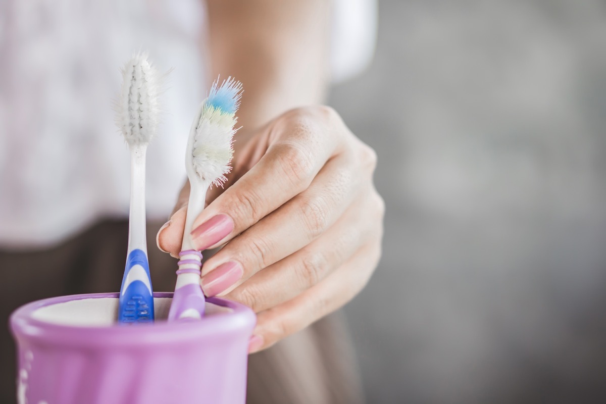 woman hand using old and destroy toothbrush closeup