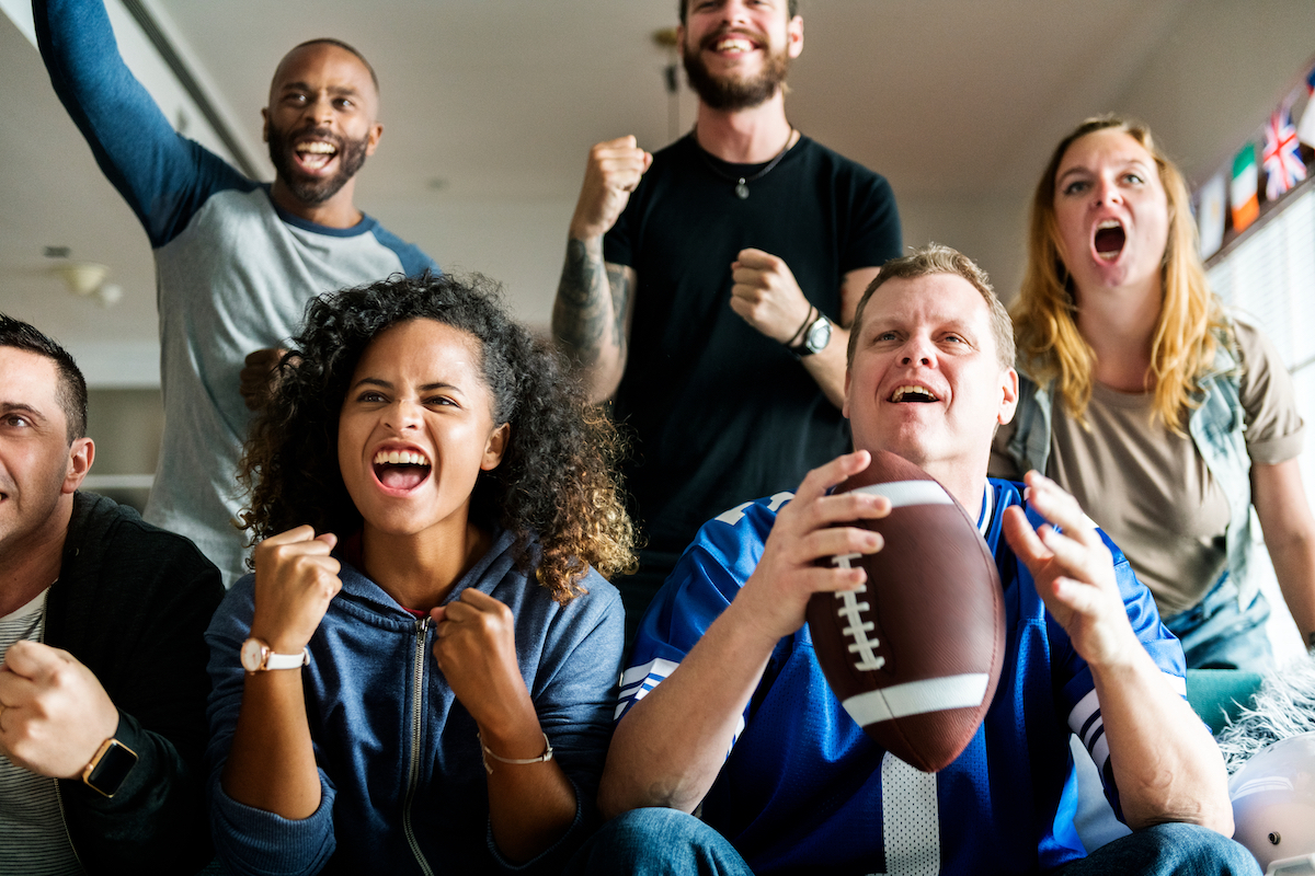 Friends cheering for football team together