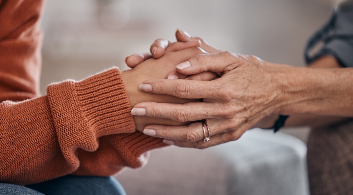 Women, holding hands and closeup for therapy, mental health support or consultation for problem on sofa. Woman, helping hand and psychologist for wellness conversation, advice or care for depression