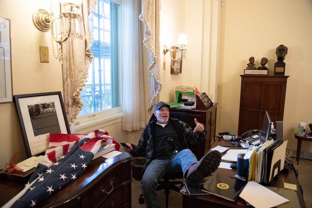 A supporter of US President Donald Trump sits inside the office of US Speaker of the House Nancy Pelosi as he protest inside the US Capitol in Washington, DC, January 6, 2021. - Demonstrators breeched security and entered the Capitol as Congress debated the a 2020 presidential election Electoral Vote Certification.