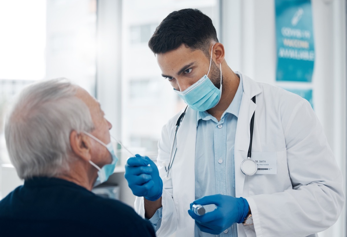 Cropped shot of a handsome young male doctor testing a senior patient for covid