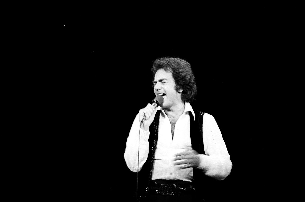 Neil Diamond performs in white wide collar shirt and black vest