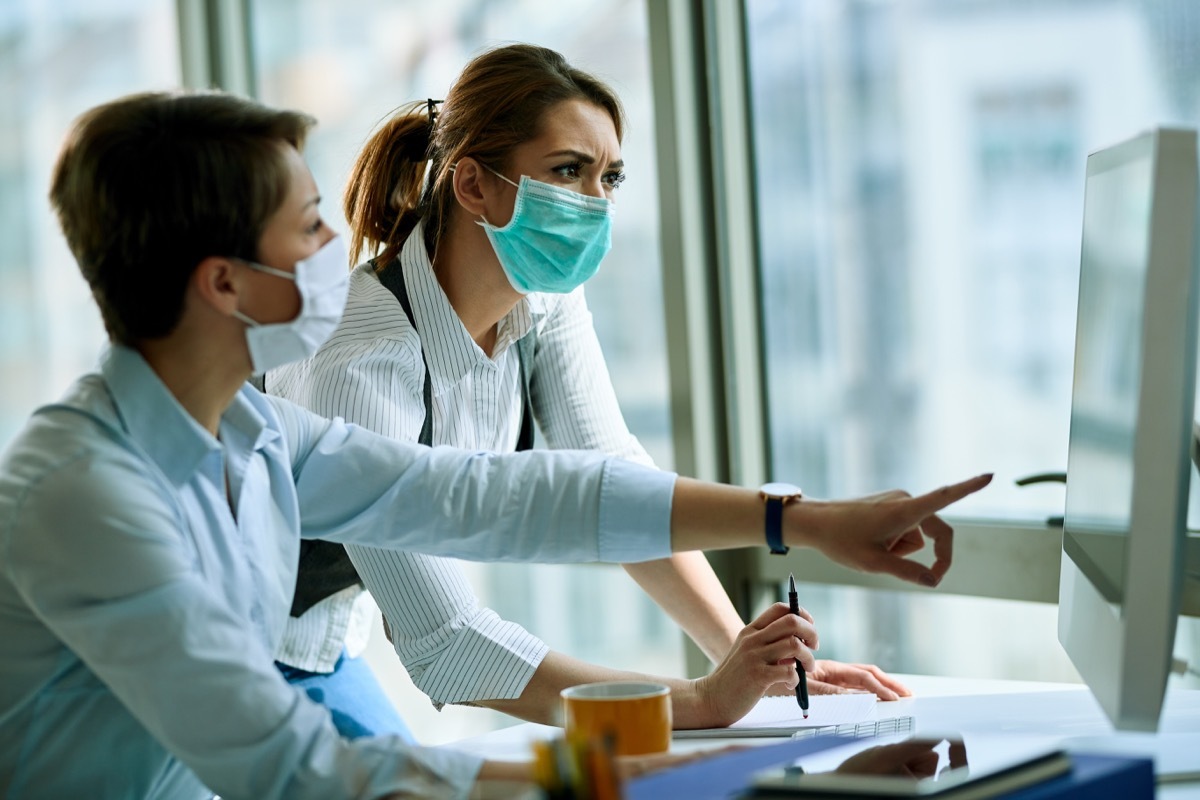 two people talking with masks on at an office