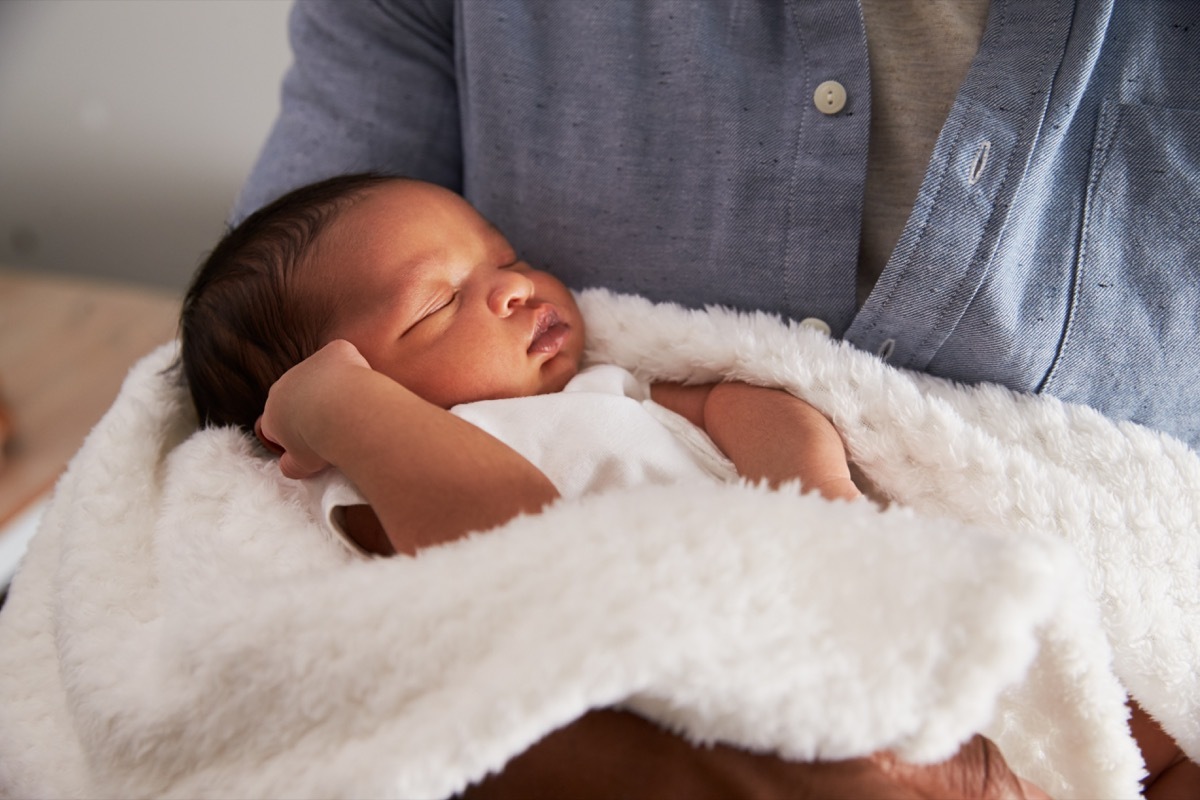 person in denim shirt holding newborn black baby